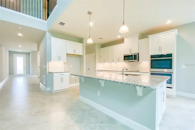 a large kitchen with a large counter top a sink stainless steel appliances and cabinets