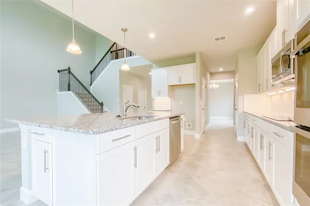 a kitchen with granite countertop white cabinets and sink
