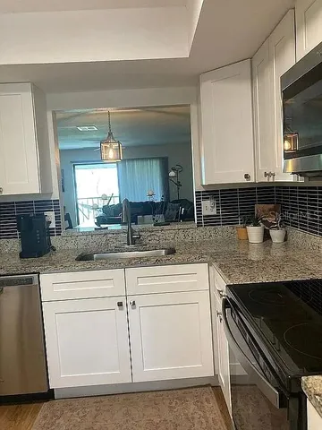 a kitchen with granite countertop white cabinets and a sink