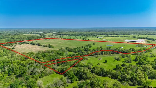 a view of a lush green outdoor space with a swimming pool and valleys in the background