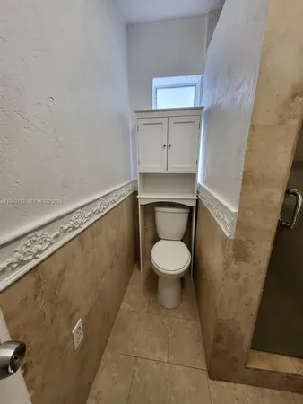 a white toilet sitting next to a white cabinet