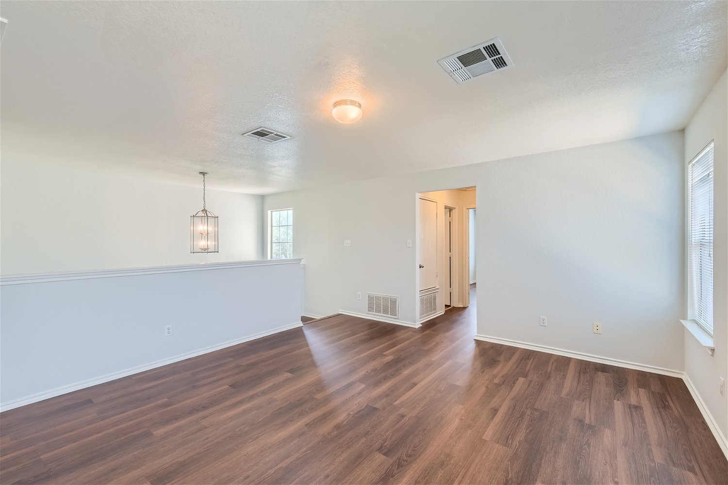 18408 Cloudmore Lane Elgin, TX 78621 - Photo 9 of 11 Rich wood flooring flows through this adaptable open-concept living area, highlighted by a modern pendant light fixture.