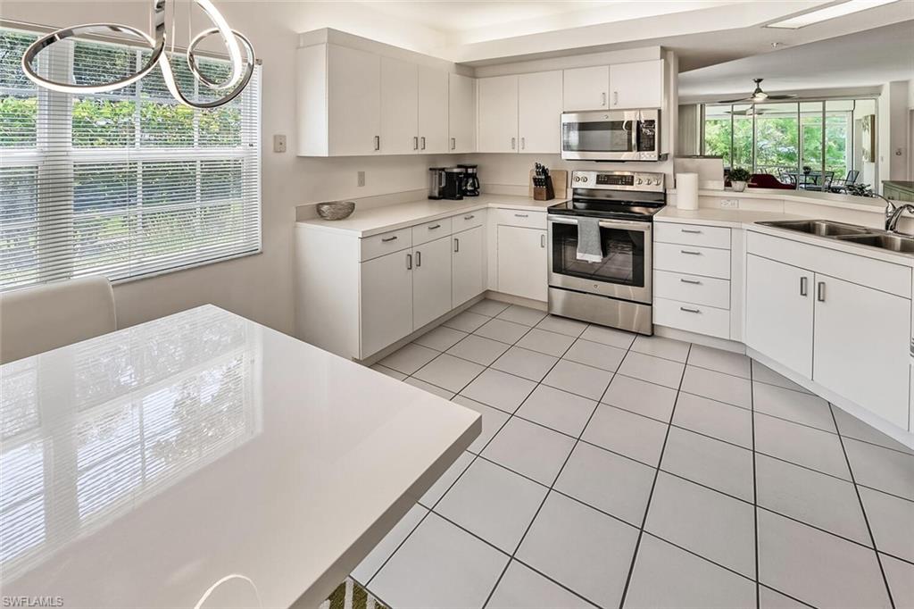 6910 Satinleaf Road North, Unit 101 Naples, FL 34109 - Photo 8 of 30 Kitchen featuring white cabinetry, ceiling fan, and stainless steel appliances