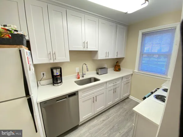 a kitchen with stainless steel appliances white cabinets sink and a refrigerator