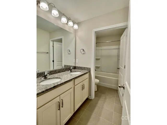 a bathroom with a granite countertop sink a toilet and shower