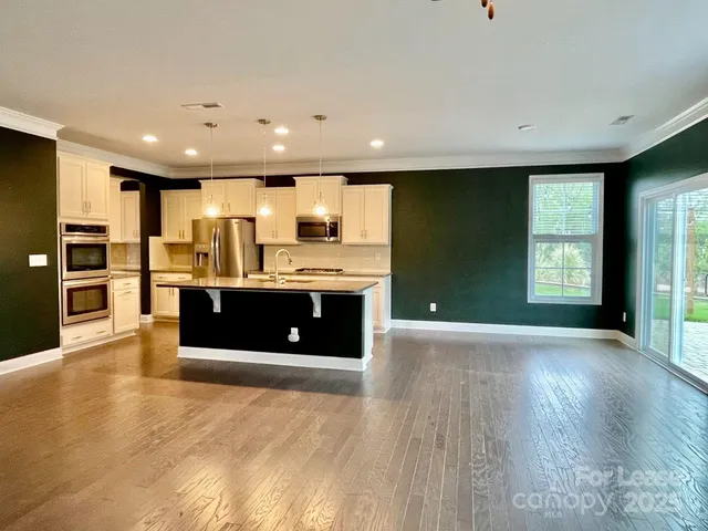 a large kitchen with stainless steel appliances a large counter top a stove and a refrigerator