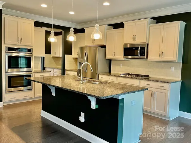 a kitchen with stainless steel appliances granite countertop a sink a stove and cabinets