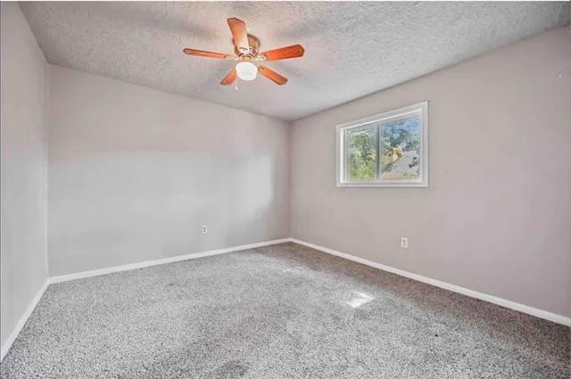 an empty room with a chandelier fan and closet