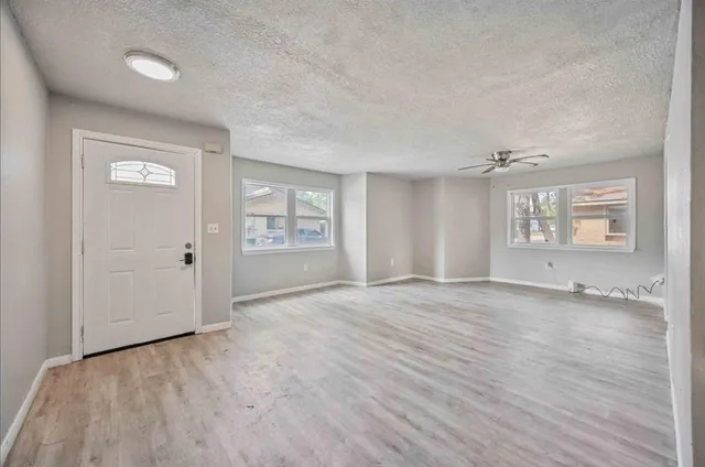 a view of an empty room with a window and wooden floor