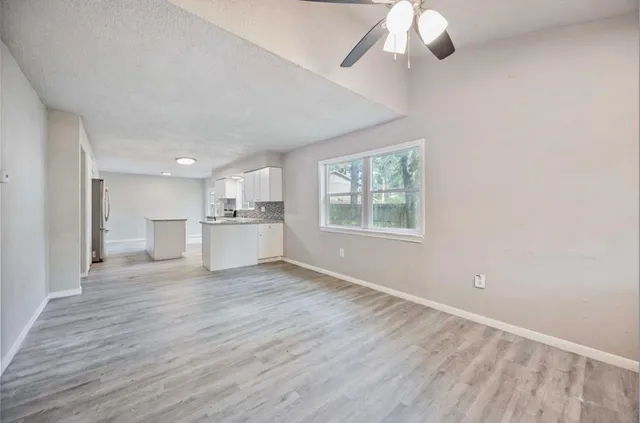 an empty room with wooden floor cabinet and windows