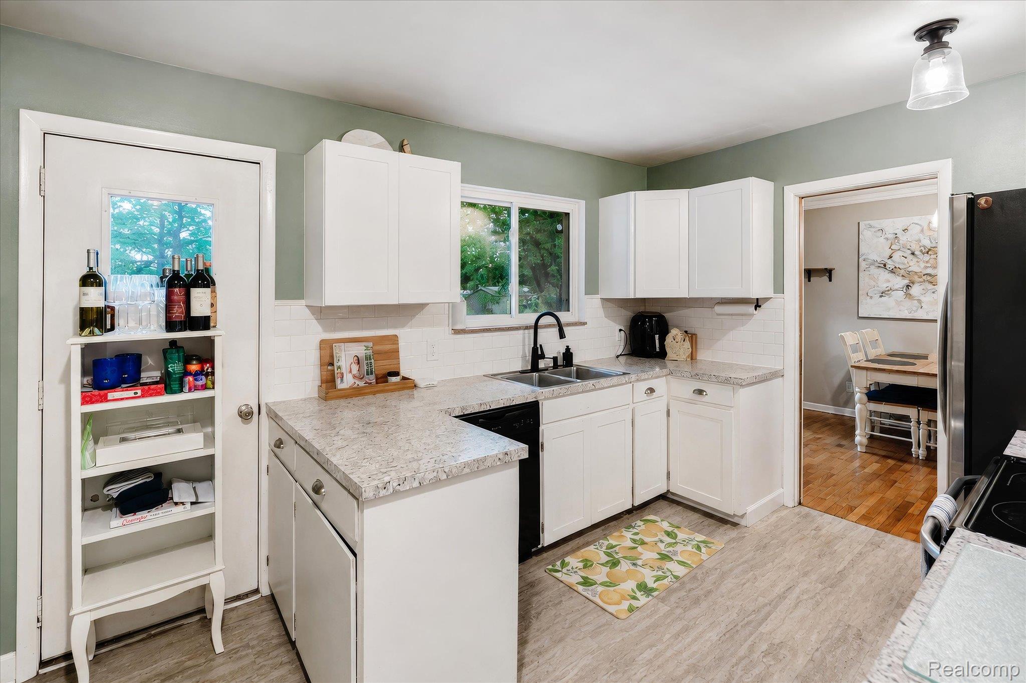 4499 South Linden Road Flint, MI 48507 - Photo 17 of 32 U-shaped kitchen with white cabinetry, light-toned countertops, and a subway tile backsplash