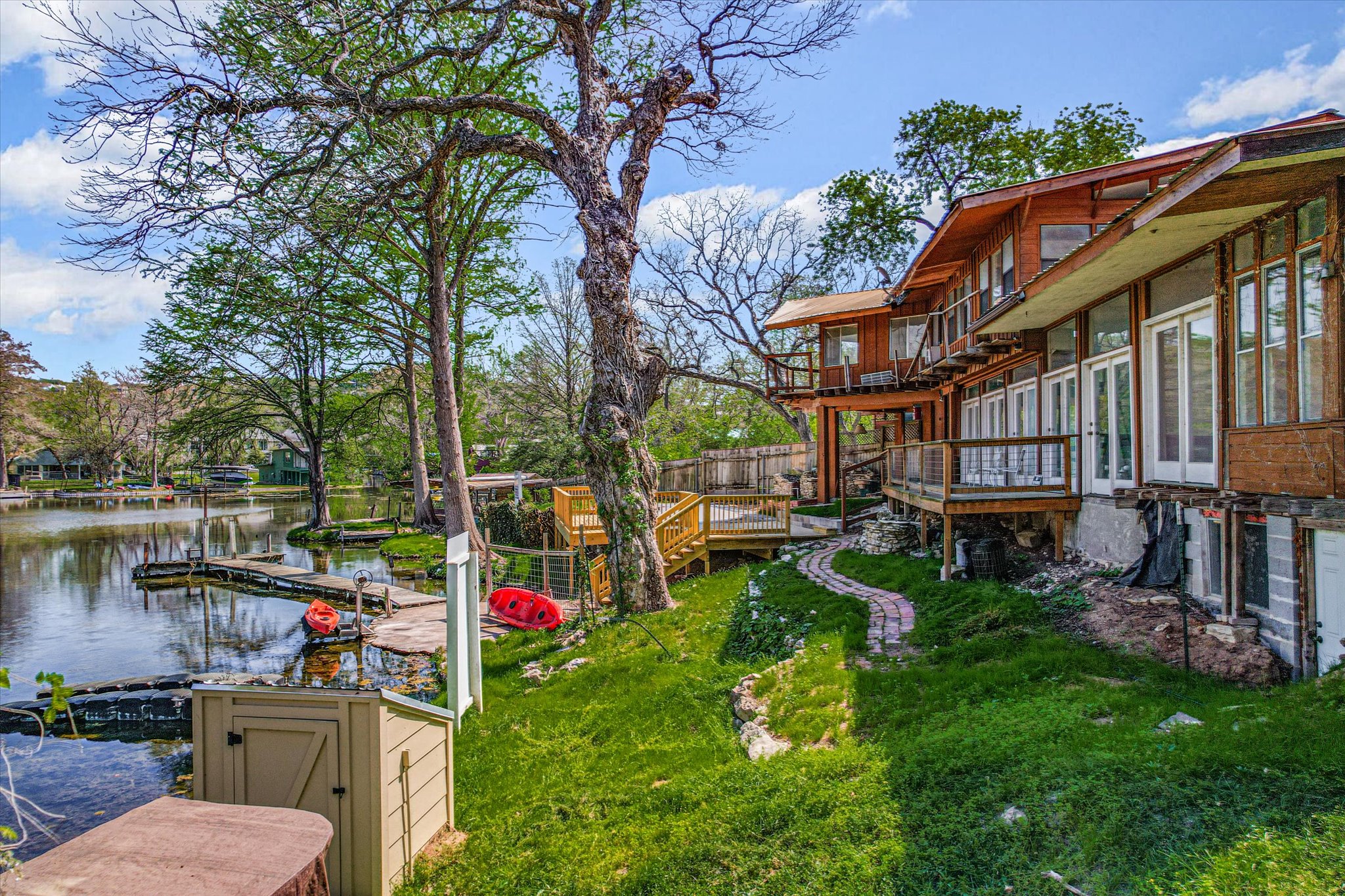 1810 Rockcliff Road Austin, TX 78746 - Photo 7 of 10 Waterfront property featuring a multi-level structure with extensive decking, multiple sets of French doors, and a private dock