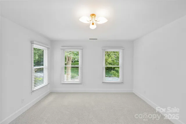 an empty room with windows and a ceiling fan