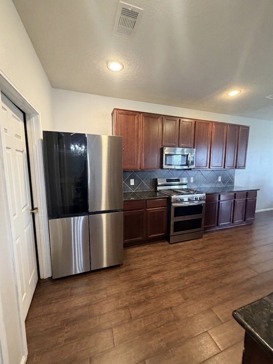 9908 Climbing Tree Street Conroe, TX 77385 - Photo 6 of 26 a kitchen with stainless steel appliances a refrigerator a stove a sink a microwave and island