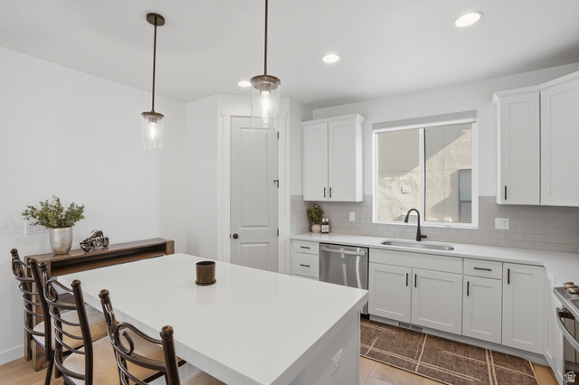 11531 Engelmann Drive Draper, UT 84020 - Photo 11 of 31 Modern kitchen featuring a large central island with solid surface countertops, white shaker cabinetry, stainless steel appliances, a matte black faucet, and pendant lighting