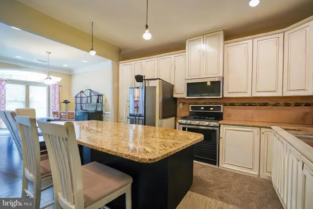 a kitchen with stainless steel appliances granite countertop a kitchen island hardwood floor sink stove dining table and chairs