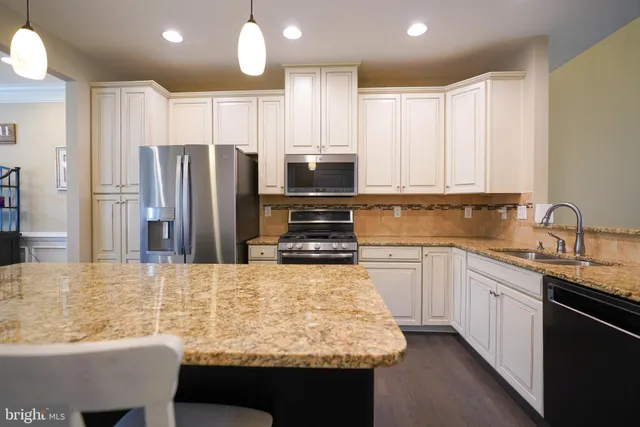 a kitchen with kitchen island granite countertop a sink stove and refrigerator
