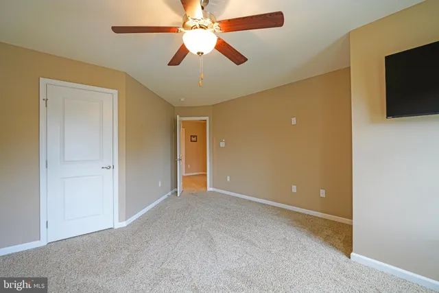 an empty room with closet and a ceiling fan