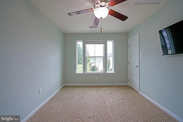 en empty room with windows and chandelier fan