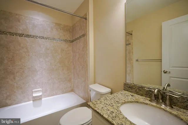 a bathroom with a granite countertop sink toilet a mirror and shower