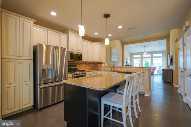 a kitchen with stainless steel appliances granite countertop a refrigerator a sink a stove a dining table and chairs