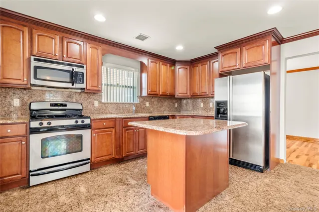 a kitchen with stainless steel appliances granite countertop a stove a sink and a refrigerator
