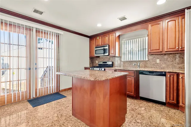 a kitchen with stainless steel appliances granite countertop a stove a sink and a refrigerator