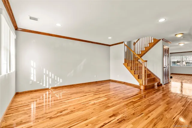 a view of an empty room with wooden floor and stairs