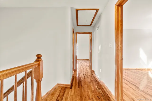 a view of a hallway with wooden floor and a bathroom