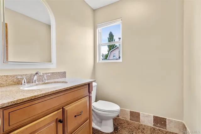 a bathroom with a granite countertop toilet sink and mirror
