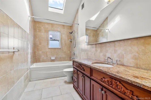 a bathroom with a granite countertop sink a toilet and bathtub