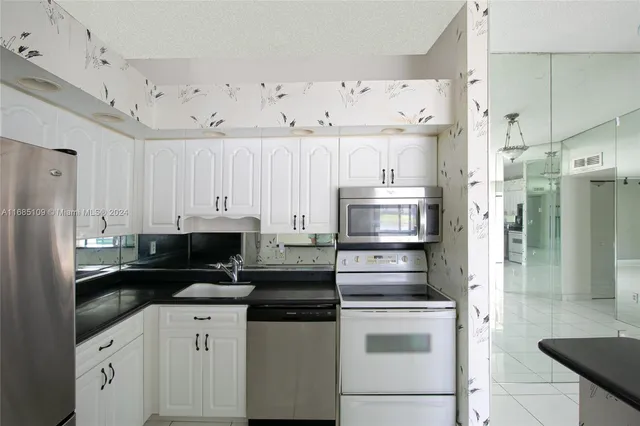 a kitchen with cabinets stainless steel appliances and sink