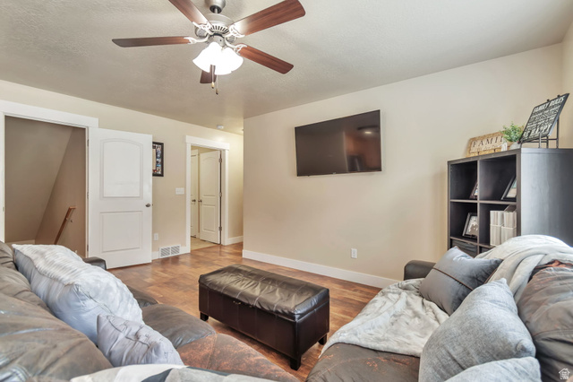 13038 Tower Ridge Drive Riverton, UT 84096 - Photo 11 of 30 Living area featuring wood-finish flooring, a ceiling fan with integrated lighting, and neutral wall paint