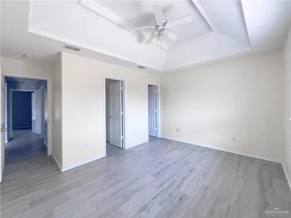 an empty room with wooden floor and ceiling fan