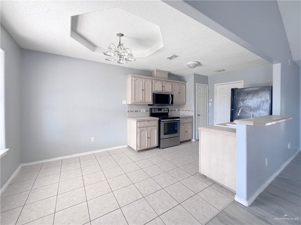 5716 North 38th Street McAllen, TX 78504 - Photo 10 of 28 a kitchen with granite countertop a refrigerator a stove top oven and a sink with cabinets