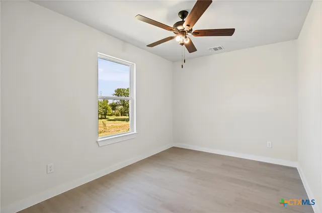 an empty room with a window and a ceiling fan