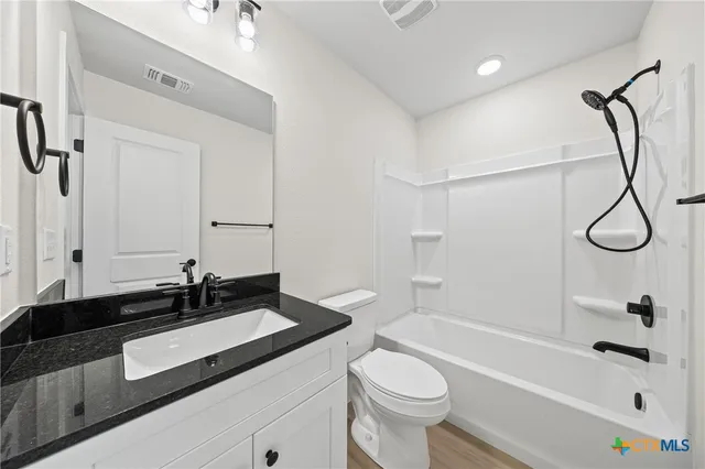 a bathroom with a granite countertop sink a toilet and bathtub