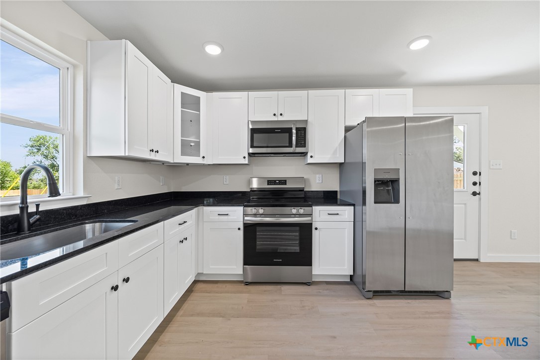 602 South 18th Street, Unit B Temple, TX 76501 - Photo 6 of 24 a kitchen with granite countertop white cabinets and stainless steel appliances