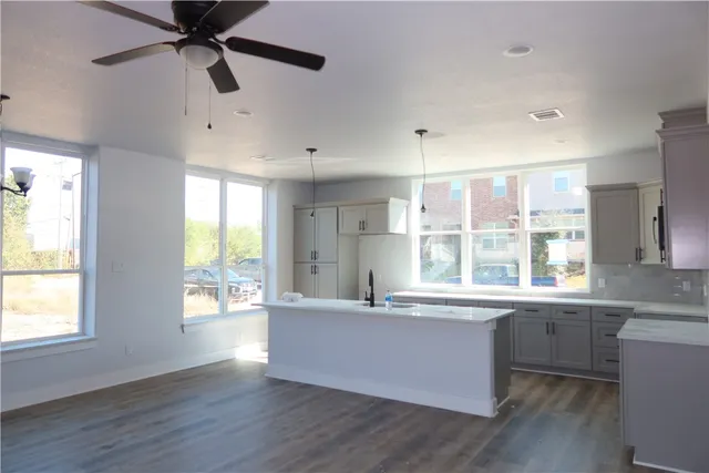 a large white kitchen with wooden floors and wide window