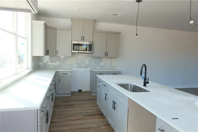 a kitchen with granite countertop a sink a counter space appliances and cabinets