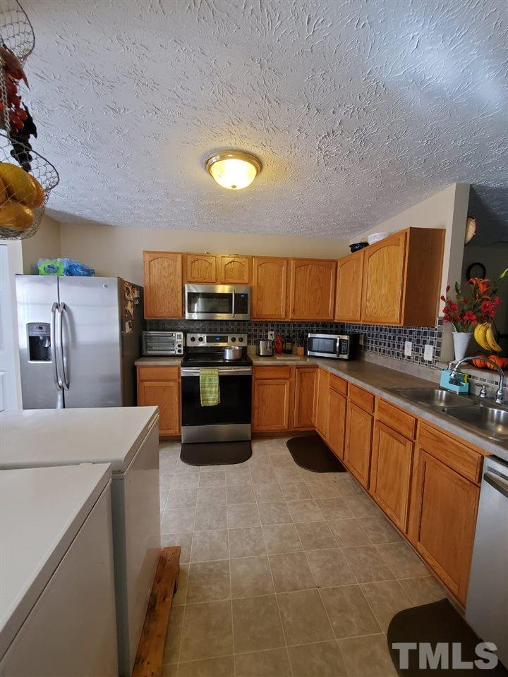 4232 Tensity Drive Raleigh, NC 27604 - Photo 6 of 13 a large kitchen with stainless steel appliances wooden cabinets a stove a counter space and a sink