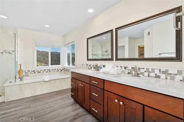 a bathroom with a tub double sink window and mirror