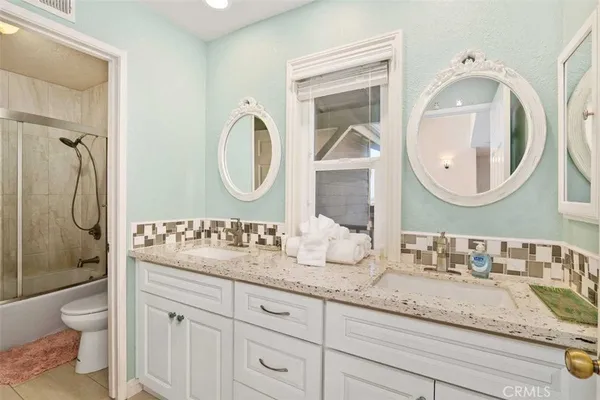a bathroom with a granite countertop toilet a sink and a mirror