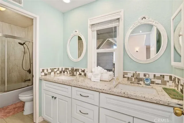 a bathroom with a granite countertop toilet a sink and a mirror