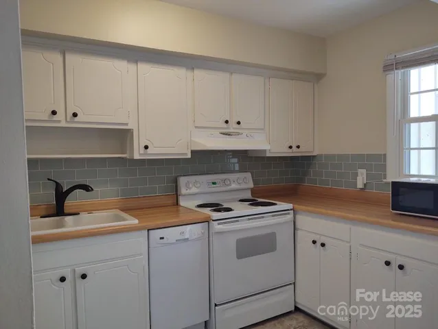 a kitchen with white cabinets and white appliances