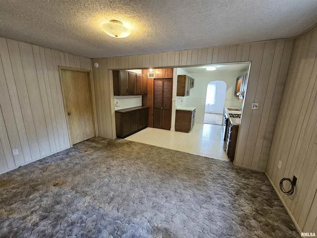 a view of a refrigerator in kitchen and an empty room