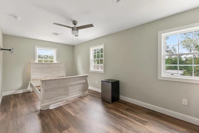a view of an empty room with a window and wooden floor