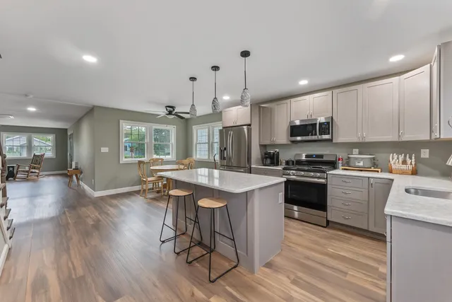 a kitchen with stainless steel appliances kitchen island granite countertop a stove a sink a refrigerator and a microwave