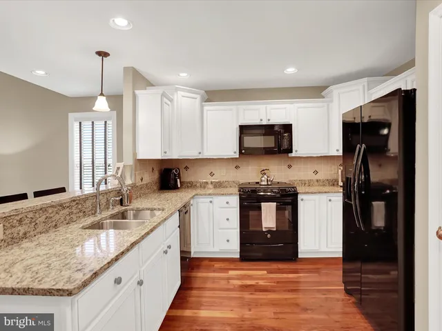 a large kitchen with stainless steel appliances granite countertop a stove a sink and a refrigerator