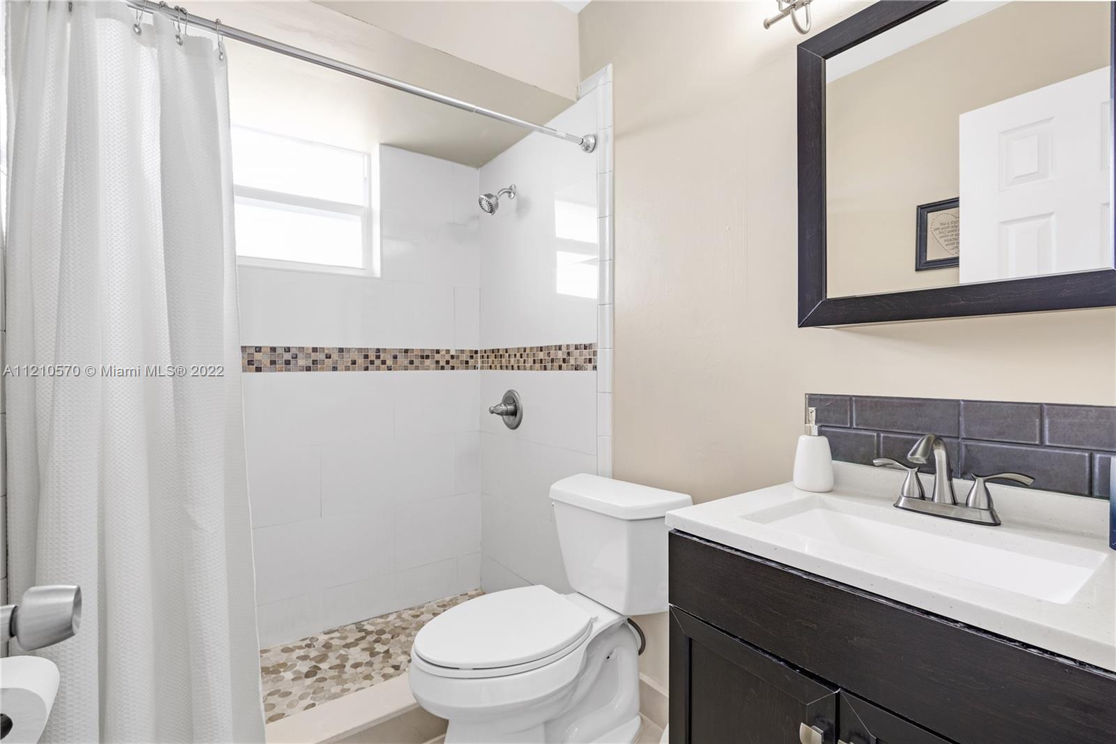 9459 Southwest 76th Street, Unit R7 Miami, FL 33173 - Photo 19 of 24 a bathroom with a sink a toilet a shower and a mirror